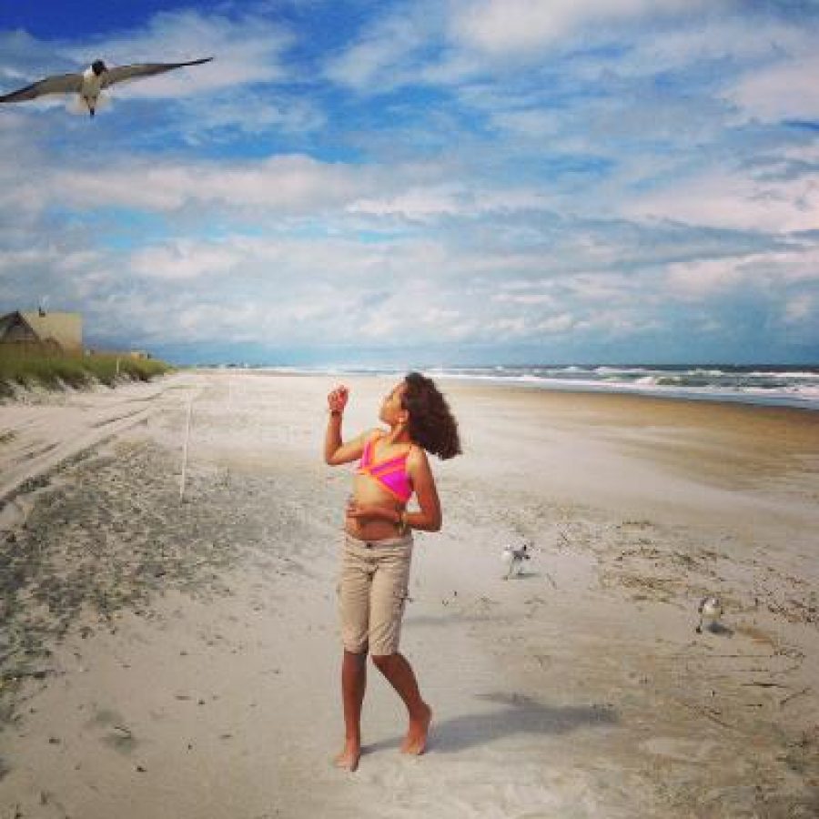 Young Girl At The Beach Looking Up At A Bird